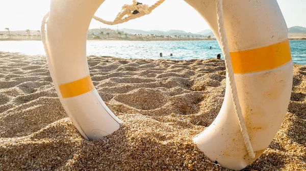 Closeup image of life saving ring to help people drowning in the sea lying on the sandy sea beach — Stock Photo, Image