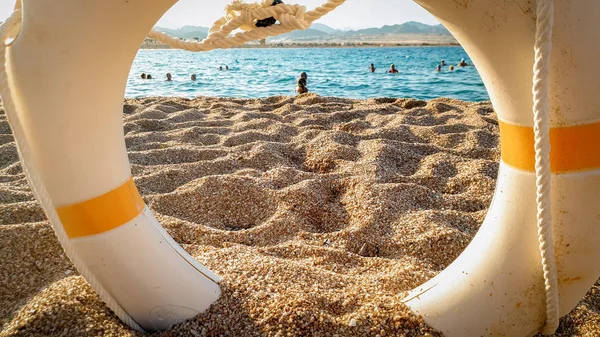 Closeup image of looking on the sandy sea beach through life saving ring — Stock Photo, Image