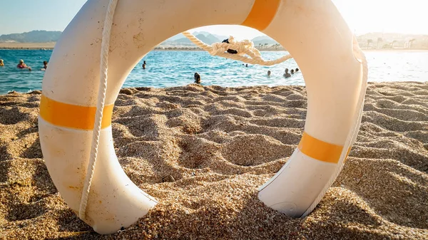 Imagen de primer plano del anillo salvavidas para ayudar a las personas que se ahogan en el mar tumbadas en la playa de arena — Foto de Stock