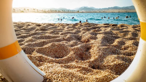 Zbliżenie obraz patrząc na piaszczystej plaży morskiej przez życie pierścień oszczędzania — Zdjęcie stockowe