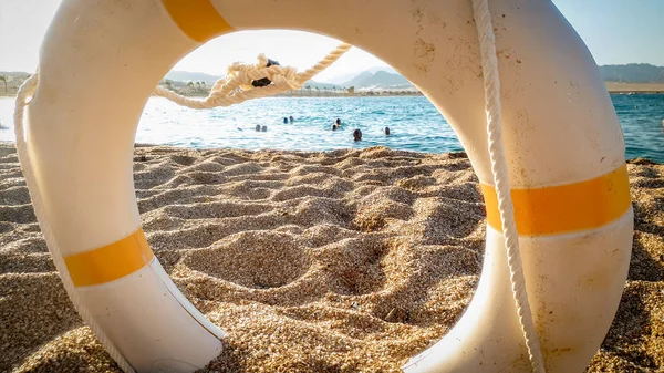 Крупный план спасающего жизнь кольца, чтобы помочь людям утонуть в море лежащих на песчаном пляже — стоковое фото