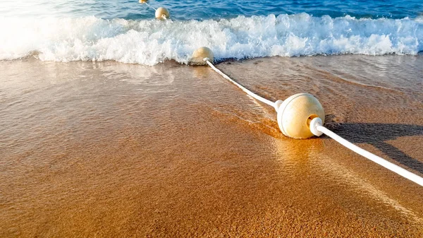 Κοντινό πλάνο της γραμμής των αιωρούμενα σημαδούρες που βρίσκονται στην υγρή άμμο στη θάλασσα ακτή — Φωτογραφία Αρχείου