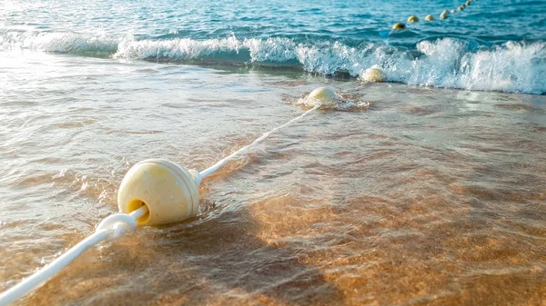 Κοντινά πλάνα όμορφη εικόνα της μεγάλης γραμμής των αιωρούμενα σημαδούρες που συνδέονται με το σχοινί που επιπλέει στη θάλασσα και βρίσκεται στην αμμώδη παραλία — Φωτογραφία Αρχείου