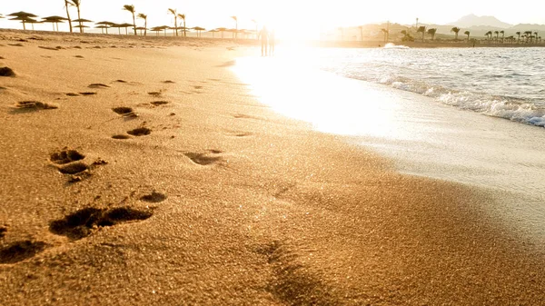 Piękny widok na słońce ustawienie nad morzem. Piękna piaszczysta plaża morska i fale toczenia nad brzegiem — Zdjęcie stockowe