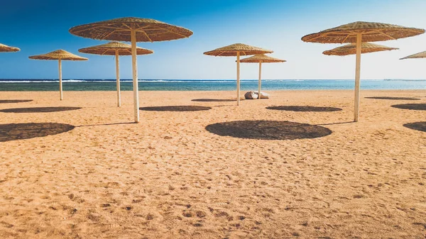Hermosa imagen de umrellas del sol en la playa en día ventoso soleado brillante — Foto de Stock