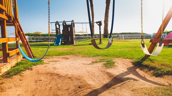 Imagen de primer plano de columpios vacíos en el parque infantil en un día soleado brillante. Nadie jugando en el parque —  Fotos de Stock