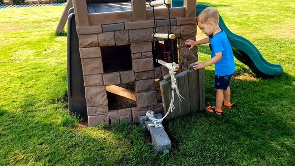 Potret anak laki-laki lucu bermain di taman bermain dengan mainan rumah plastik — Stok Foto