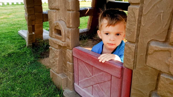 Retrato de menino adorável criança brincando no playground com casa de plástico de brinquedo no parque — Fotografia de Stock