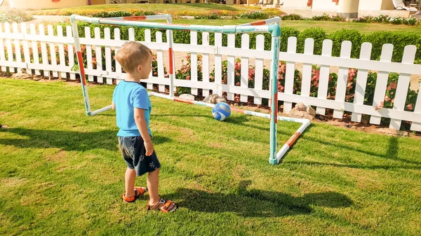 Image of happy smiling toddler boy scoring goal on football field at park. Active children doings sports — Stock Photo, Image