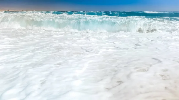 Photo rapprochée de belles vagues qui se brisent sur le rivage. Du sable humide et des éclaboussures d'eau sur la plage — Photo