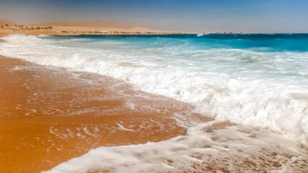 Foto de cerca de hermosas olas marinas rompiendo en la orilla. Arena húmeda y salpicaduras de agua en la playa — Foto de Stock