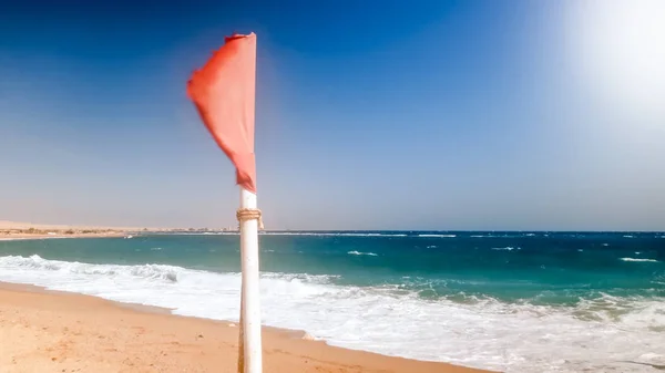 Imagen de primer plano de la bandera roja de advertencia ondeando bajo un fuerte viento en el mar antes de la tormenta —  Fotos de Stock