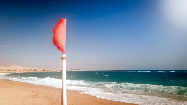 Imagen de primer plano de la bandera roja de advertencia ondeando bajo un fuerte viento en el mar antes de la tormenta —  Fotos de Stock