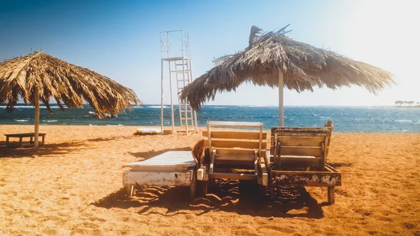 Hermosa foto tonificada de playa de mar abandonada con viejas tumbonas de madera o tumbonas en la orilla en un día soleado y ventoso. Concepto de crisis en los viajes o el turismo — Foto de Stock
