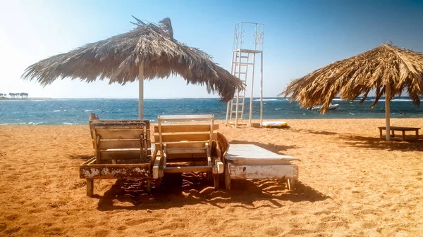 Hermosa foto de viejas tumbonas de madera o tumbonas en la playa vacía en el soleado día ventoso — Foto de Stock