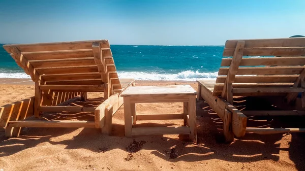 Hermosa foto de viejas tumbonas de madera o tumbonas en la playa vacía en el soleado día ventoso —  Fotos de Stock