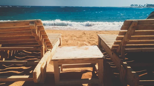 Hermosa foto tonificada de playa de mar abandonada con viejas tumbonas de madera o tumbonas en la orilla en un día soleado y ventoso. Concepto de crisis en los viajes o el turismo —  Fotos de Stock