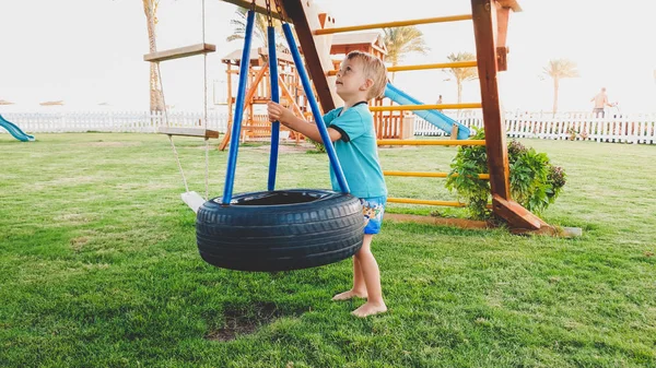 Image of cute little toddler boy playing with swings on the palyground at park — Stock Photo, Image