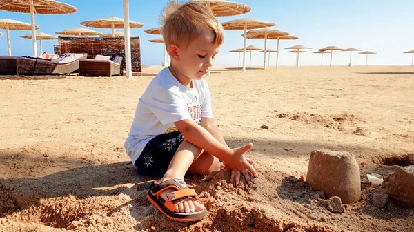 Obraz 3-letniego małego chłopca malucha siedzącego na plaży morskiej i budynku zamku z mokrego piasku — Zdjęcie stockowe