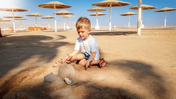 Obraz 3-letniego małego chłopca malucha siedzącego na plaży morskiej i budynku zamku z mokrego piasku — Zdjęcie stockowe