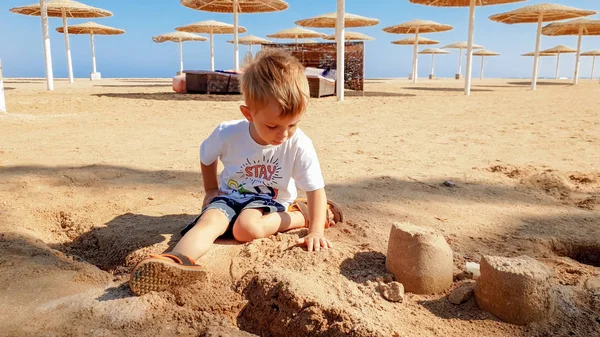 Portret Cute Little Boy podejmowania piasku zamek na plaży Morza — Zdjęcie stockowe