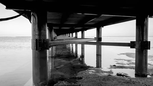 Imagem em preto e branco de baixo do longo cais no mar — Fotografia de Stock