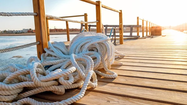 Closeup photo of ship rope lying on wooden pier in the sea. Amazing photo at ocean port — Stock Photo, Image