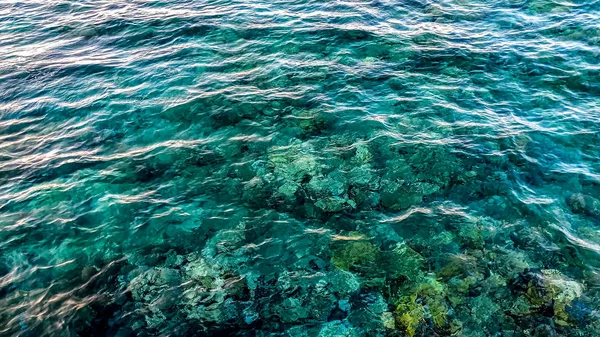Foto de agua de mar turquesa beutiful y rocas que mienten en el fondo — Foto de Stock