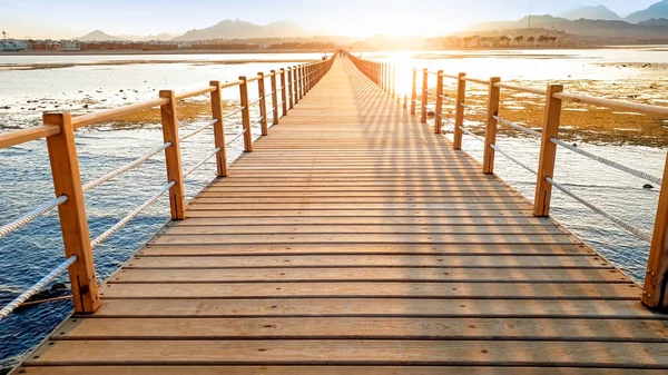 Прекрасне зображення довгого дерев'яного пірсу в е. Дивовижний захід сонця над мостом в океані — стокове фото