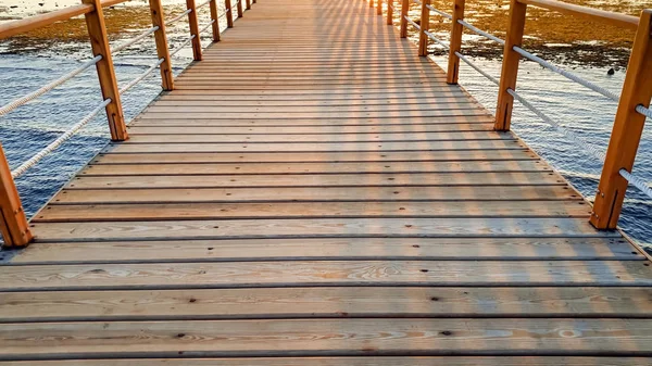 Hermosa imagen de largo muelle de madera en el ea. Increíble puesta de sol sobre el puente en el océano — Foto de Stock