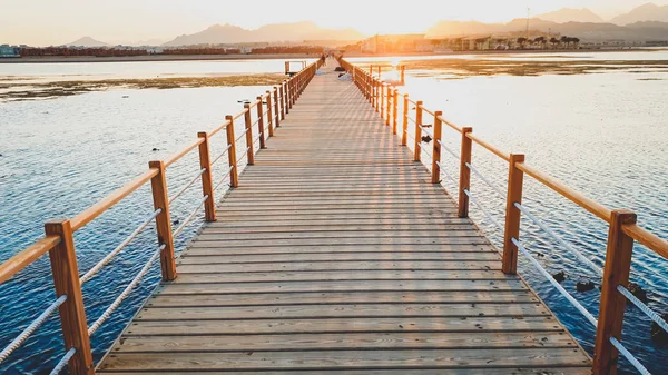 Прекрасне зображення довгого дерев'яного пірсу в е. Дивовижний захід сонця над мостом в океані — стокове фото