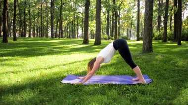 Orta yaşlı gülümseyen mutlu kadın meditasyon ve ormanda çim üzerinde yoga egzersizleri yapıyor Görüntü. Parkta fitness ve germe pracitising ise onun fiziksel ve ruhsal sağlığı bakımı Kadın