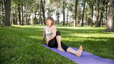 Photo of smiling woman doing yoga and fitness exercises. Middle aged people taking care of their health. Harmony of body and mind in nature clipart