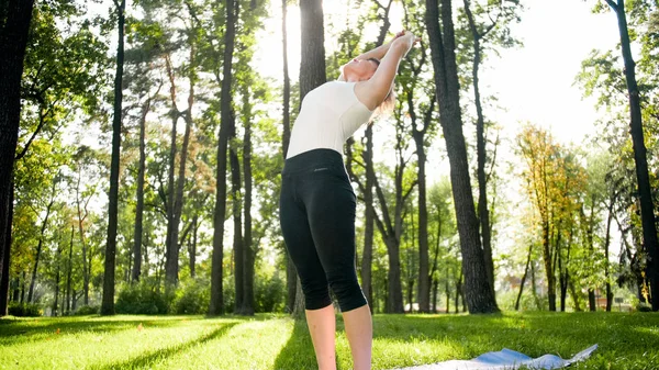 Zdjęcie uśmiechniętej kobiety robi jogi i ćwiczeń fitness. Ludzie w średnim wieku dbają o swoje zdrowie. Harmonia ciała i umysłu w przyrodzie — Zdjęcie stockowe