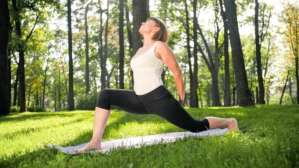 Foto de mulher sorridente de meia-idade praticando ioga asana. Persong meditando na natureza. Equilíbrio e harmonia de corpo e mente — Fotografia de Stock
