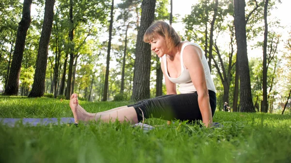 Yoga ve fitness egzersizleri yapan gülümseyen kadının fotoğrafı. Orta yaşlı insanlar sağlıklarına bakıyorlar. Doğadaki beden ve zihin uyumu — Stok fotoğraf