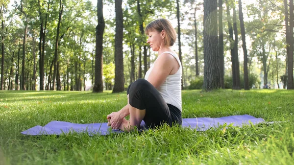 Foto de mulher sorridente fazendo exercícios de ioga e fitness. Pessoas de meia-idade cuidando de sua saúde. Harmonia de corpo e mente na natureza — Fotografia de Stock