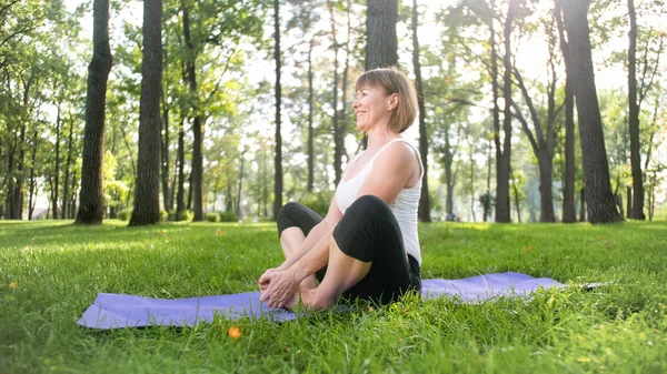 Photo d'une femme d'âge moyen pratiquant le yoga ou le fitness sur de l'herbe verte fraîche au parc. Santé physique et mentale des femmes. Personne dans la méditation et l'harmonie pf corps et âme — Photo