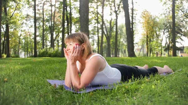 Foto de mulher sorridente fazendo exercícios de ioga e fitness. Pessoas de meia-idade cuidando de sua saúde. Harmonia de corpo e mente na natureza — Fotografia de Stock