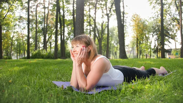 Foto de mujer sonriente de mediana edad practicando yoga asana. Persona meditando en la naturaleza. Equilibrio y armonía de cuerpo y mente — Foto de Stock
