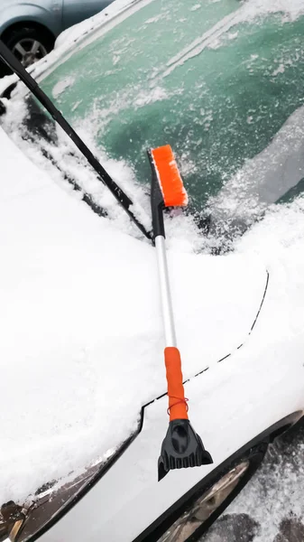 Closeup image of brush lying on the snow covered white car — Stock Photo, Image