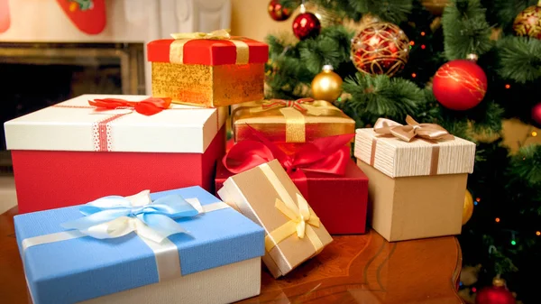 Imagem de close-up de grande montão de caixas coloridas de presentes de Natal e presentes contra árvore de Natal decorada com guirlandas e bolas — Fotografia de Stock