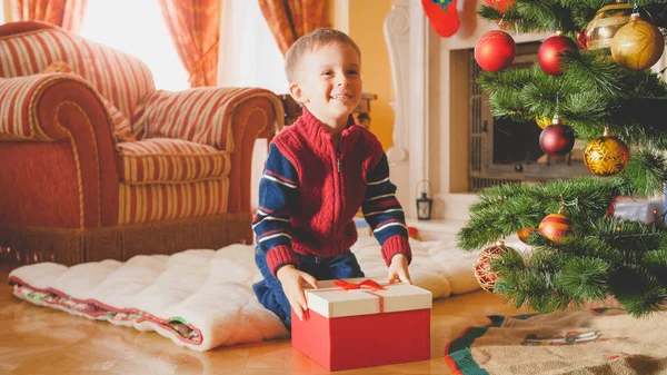 Retrato tonificado de garotinho rindo recebendo seus presentes e presentes no Natal na manhã — Fotografia de Stock