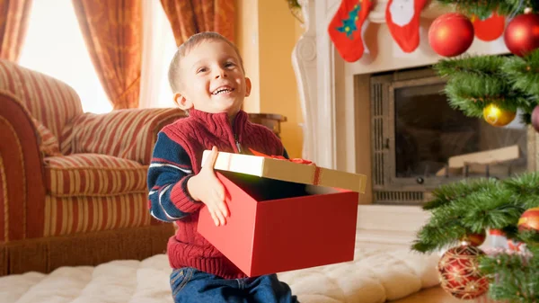 Retrato de niño sonriente feliz sosteniendo y abriendo una caja grande con regalos en Navidad o Año Nuevo — Foto de Stock