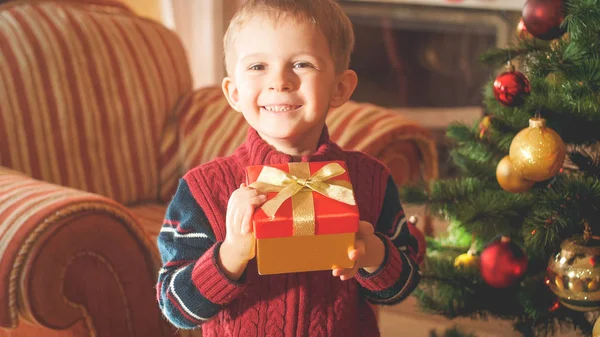 Closeup tonificado retrato de feliz sorrindo menino segurando caixa com presente de Natal ou presente e olhando na câmera — Fotografia de Stock