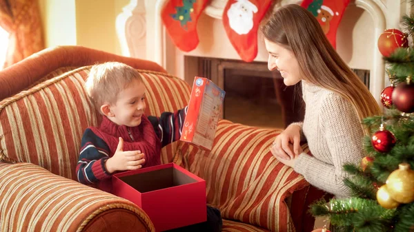 Porträtt av Happy glad liten pojke tar leksak ur lådan med julklapp. Perfekt bild för vintersemestrar och fester — Stockfoto