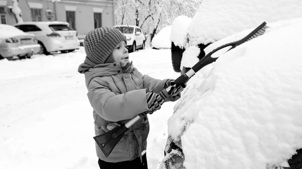 Närbild foto av leende lycklig söt pojke i beige kappa och hatt, ha kul att spela i snön på vintern efter snöfall — Stockfoto