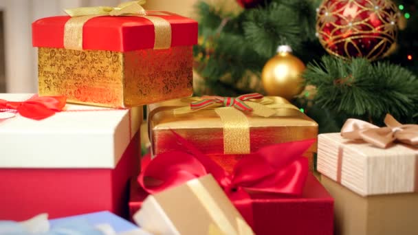 カメラのクローズアップ4k映像は、ゆっくりとライトやクリスマスツリーの上にクリスマスプレゼントやプレゼントの多くに向かって移動します。あなたの冬の休日やお祝いのための完璧なショット — ストック動画