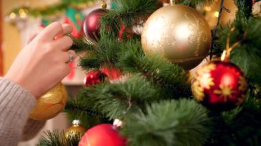 Yün kazak genç kadın altın bauble ile Noel ağacı dekorasyon ise Noel ağacı üzerinde kaydırma kamera Closeup 4k görüntüleri.