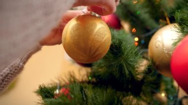 Noel ağacı dalı altın süslü bauble koyarak kadın elleri Closeup 4k video. Kış tatilleriniz ve kutlamalarınız için mükemmel çekim